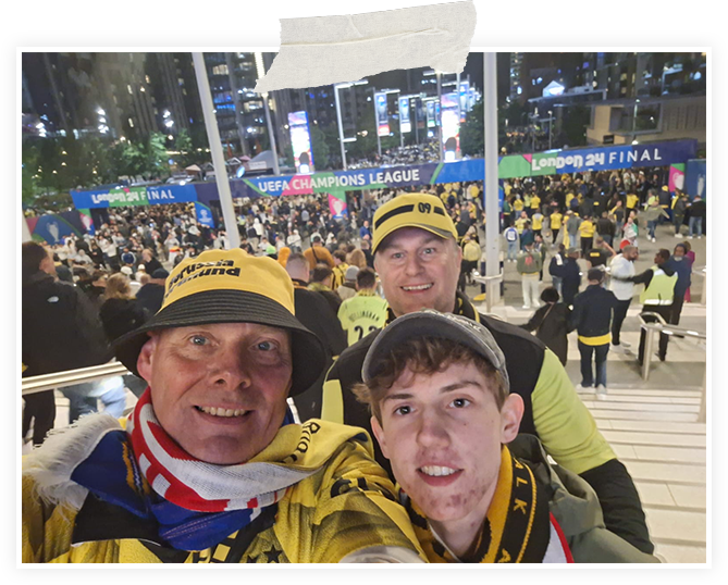 Selfie dreier Fans mit BVB-Mützen und Schals im vollen Stadion, als Polaroid-Foto gestaltet.