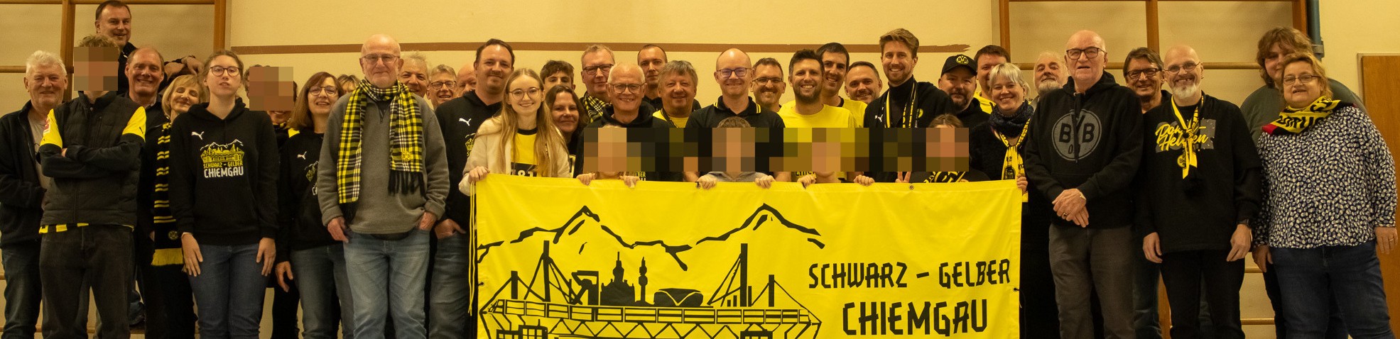 Sehr schmaler Streifen eines Gruppenbilds: Mitglieder in Schwarz-Gelb stehen hinter dem gelben Fanclub-Banner.