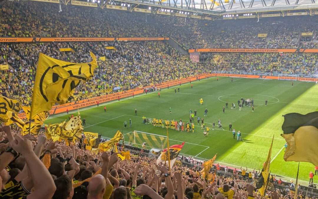 Volle Tribüne mit schwarz-gelben Fahnen unter dem gelben Stahldach, Blick auf das Spielfeld.