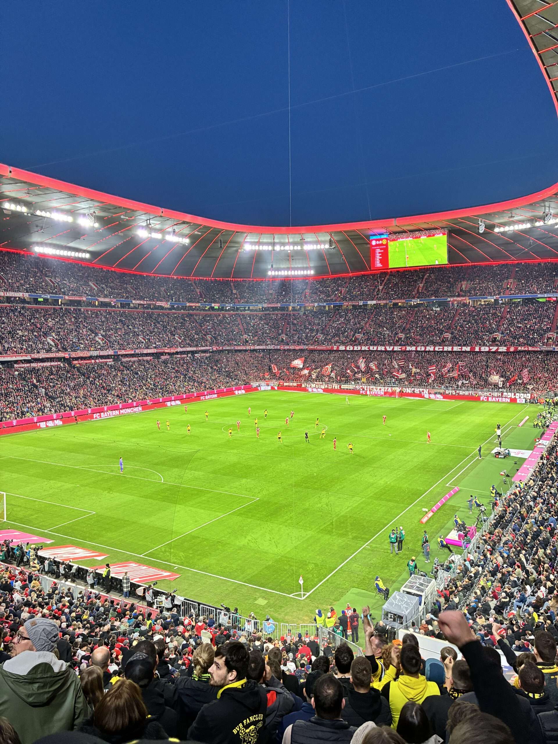 Weiter Blick aus dem Gästeblock über das Spielfeld und die vollen Ränge unter dem Stadiondach.