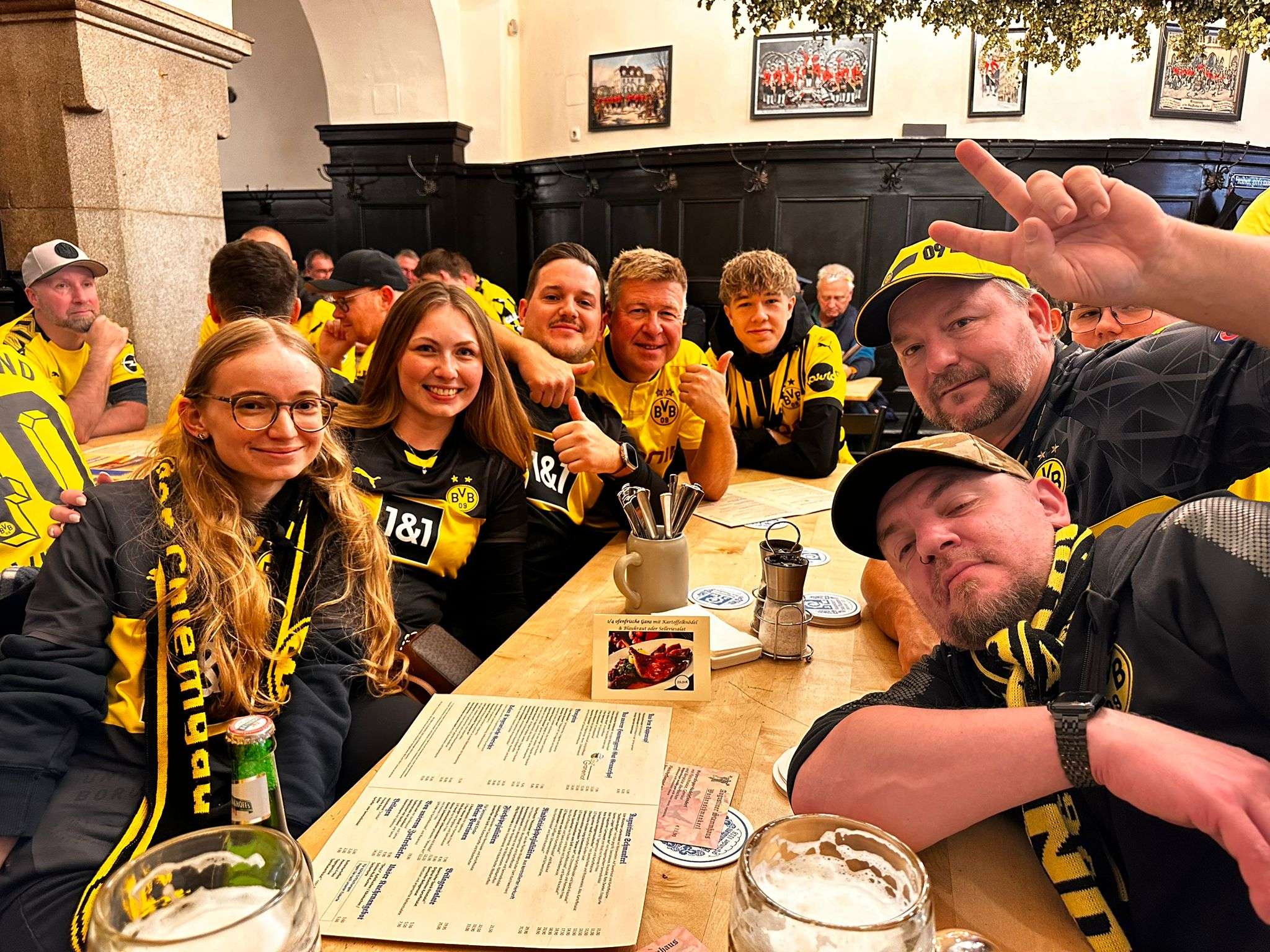 Rund zehn Mitglieder mit BVB-Schals sitzen gut gelaunt an einem Wirtshaustisch mit Speisekarten.