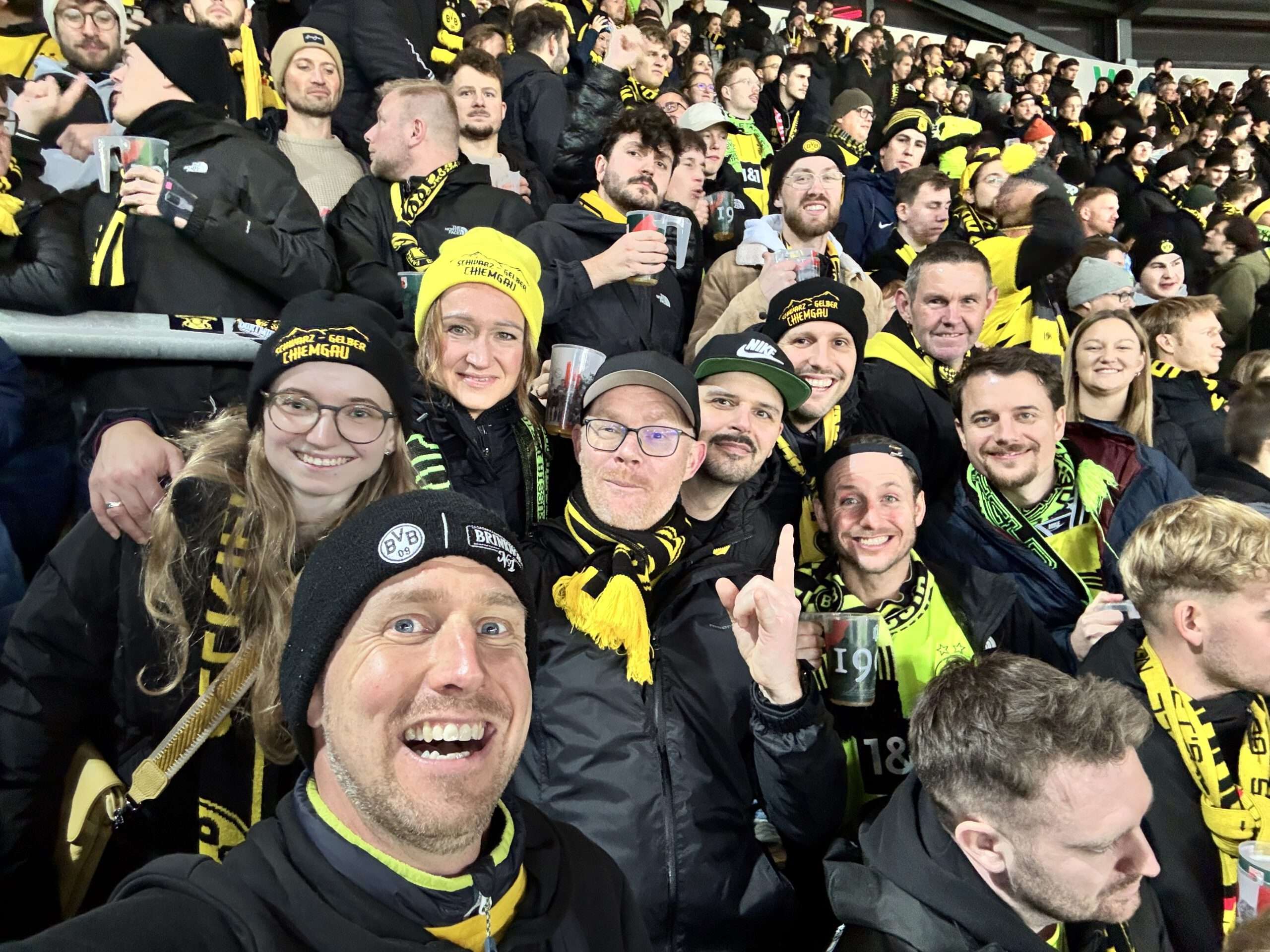 Viele gut gelaunte Fans mit Mützen und BVB-Schals drängen sich für ein Selfie im Gästeblock.