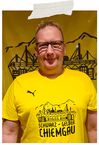 Angeheftetes Foto: lächelnder Mann mit Brille im gelben Fanclub-T-Shirt vor dem gelben Fanclub-Banner.