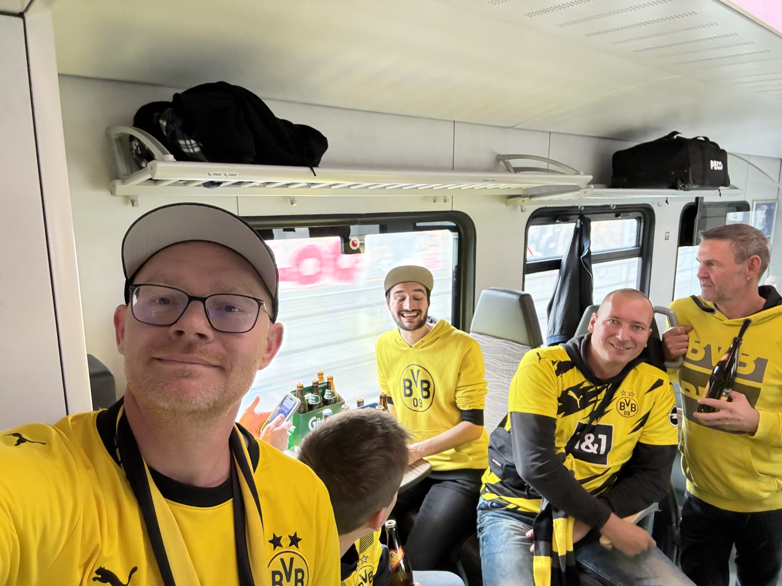 Mitglieder in gelben BVB-Trikots sitzen in einem Kleinbus, vorne ein Mann mit Kappe beim Selfie.